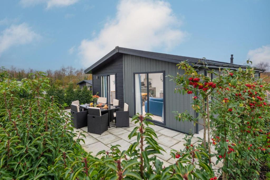a black shed with a patio in a garden at Bluebell Lodge, 29 Roadford Lake Lodges in Lifton