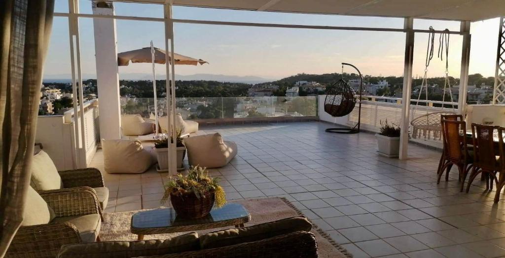 a patio with chairs and tables on a balcony at Villasonboard Vouliagmeni Penthouse Veranda Sea-view & beach in Athens