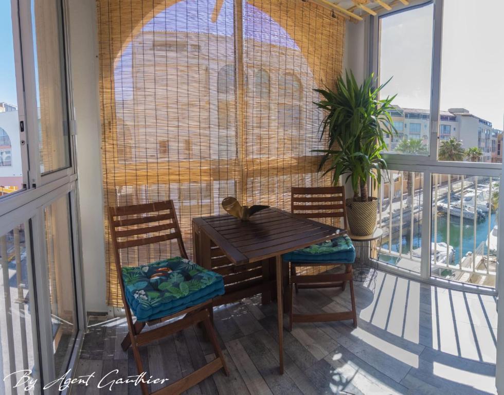 een tafel en stoelen op een balkon met ramen bij Charmant 2 pièces les pieds dans l'eau in Sète