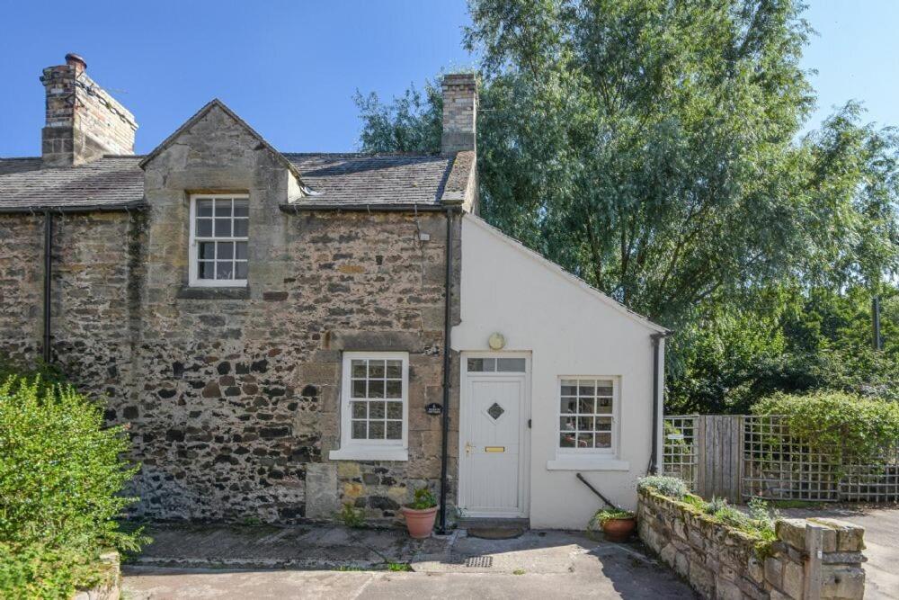an old brick house with a white door and windows at Dunlin Cottage in Bamburgh