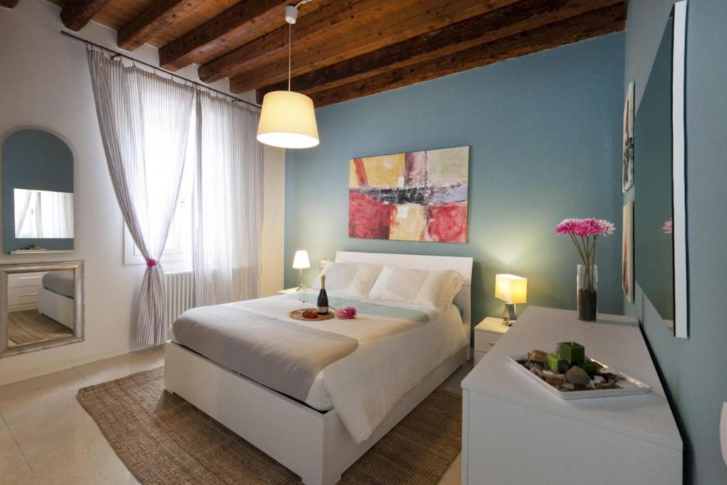 a bedroom with a white bed and a blue wall at Appartamenti Sofia & Marilyn in Castelfranco Veneto