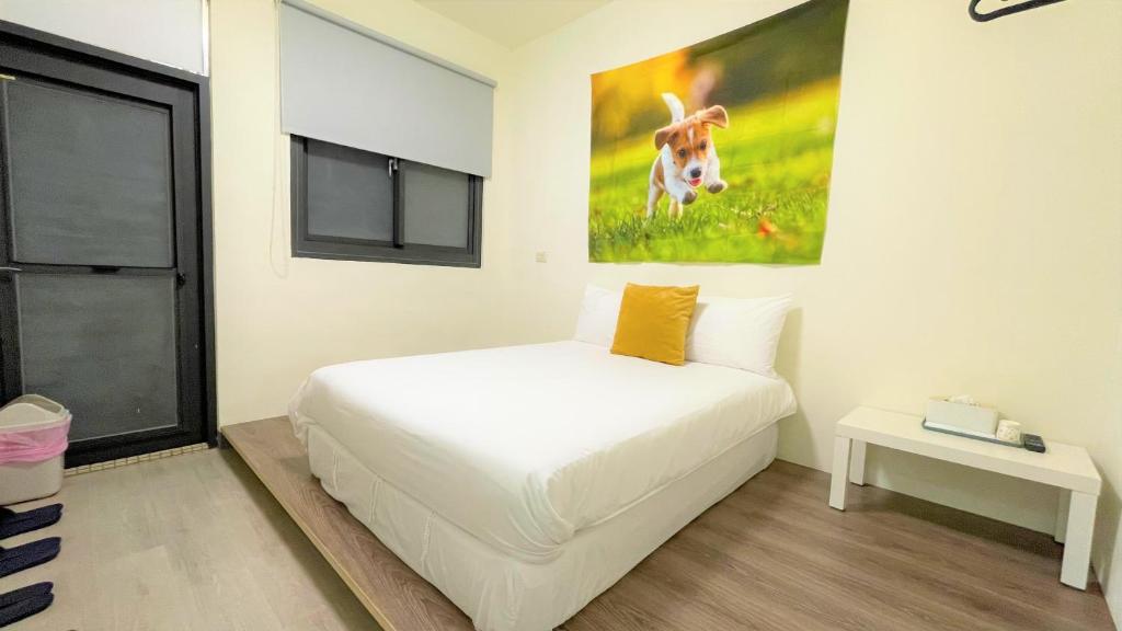 ein Schlafzimmer mit einem weißen Bett und einem Gemälde an der Wand in der Unterkunft Fengjia AS House in Taichung