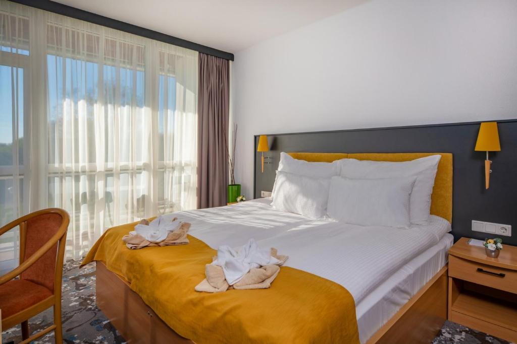 Una habitación de hotel con una cama con toallas. en Zsóry Liget Hotel & Spa Superior en Mezőkövesd