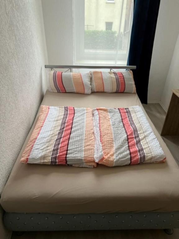2 Betten in einem kleinen Zimmer mit Fenster in der Unterkunft Zum Bahnhof in Zwickau