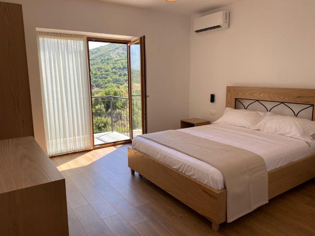 sypialnia z dużym łóżkiem i dużym oknem w obiekcie Bujtina GleAlb w mieście Tepelenë