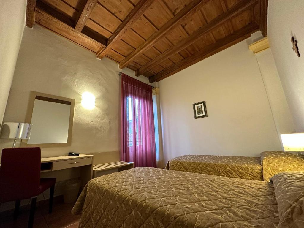 a bedroom with two beds and a desk and a mirror at Domus San Bernardino in Verona