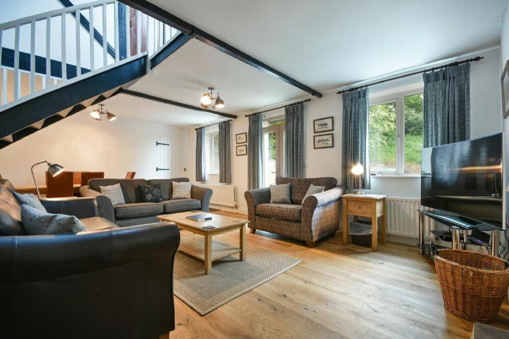 sala de estar con sofá y TV en Old Stable Cottage, en Alnmouth