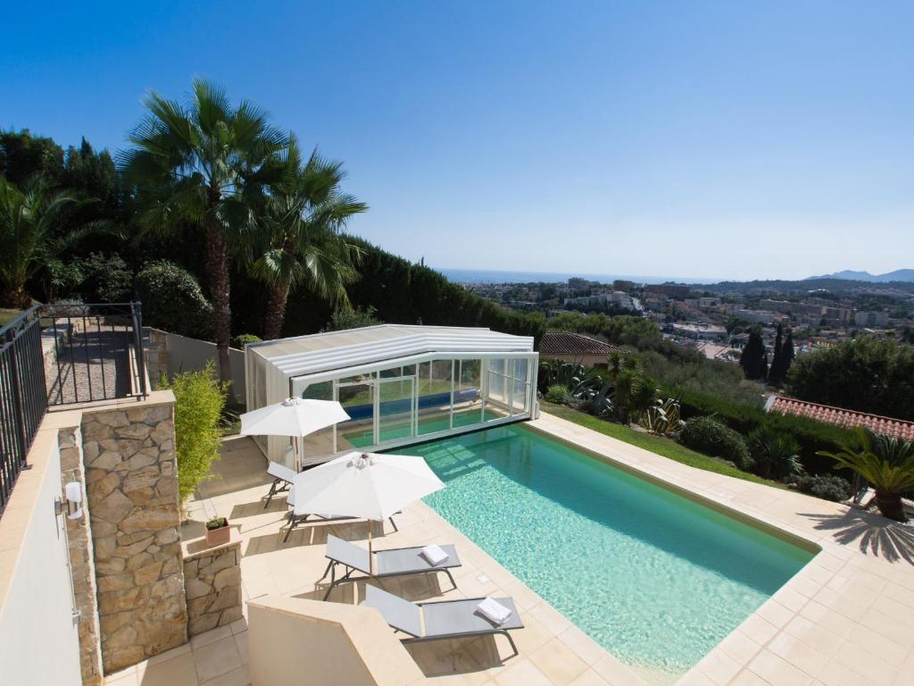 a swimming pool with umbrellas and a villa at Les chambres d'hôtes de Mougins in Mougins