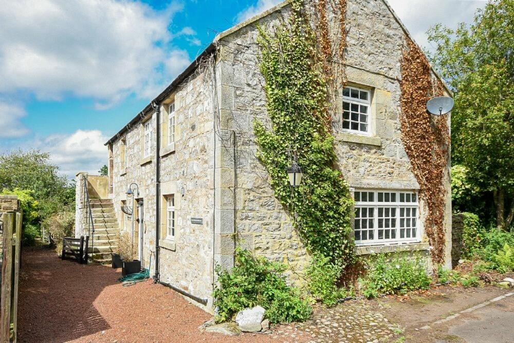 an old stone building with ivy on the side of it at Stonecrop Cottage in Alwinton