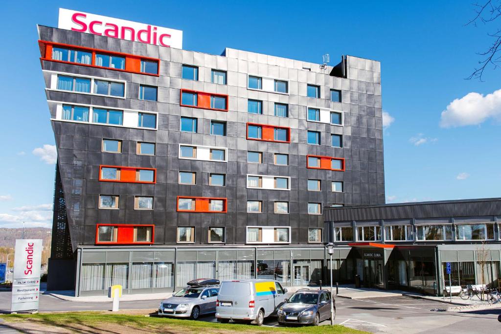 un grand bâtiment avec des voitures garées dans un parking dans l'établissement Scandic Elmia, à Jönköping
