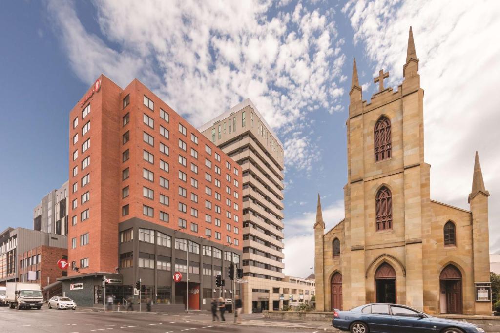 uma igreja e um edifício com um carro numa rua em Travelodge Hotel Hobart em Hobart