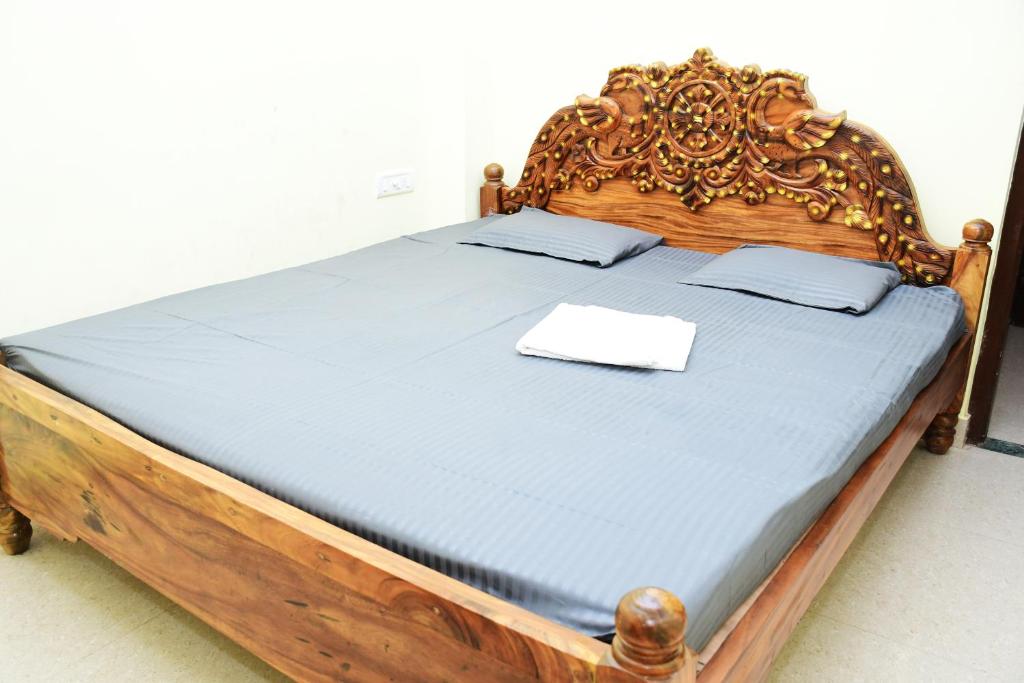 a bed with a wooden headboard with a white paper on it at HOTEL DREAM PALACE in Puri