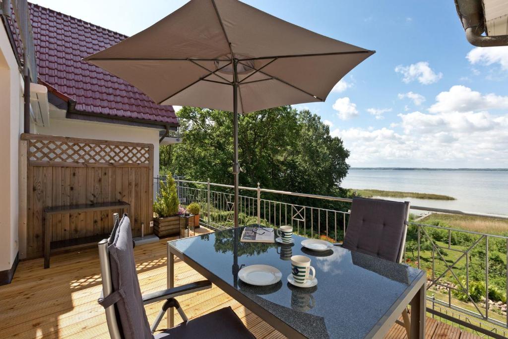 une terrasse avec une table et un parasol et l'océan dans l'établissement Haus am Kölpinsee App 3 3, à Kölpinsee
