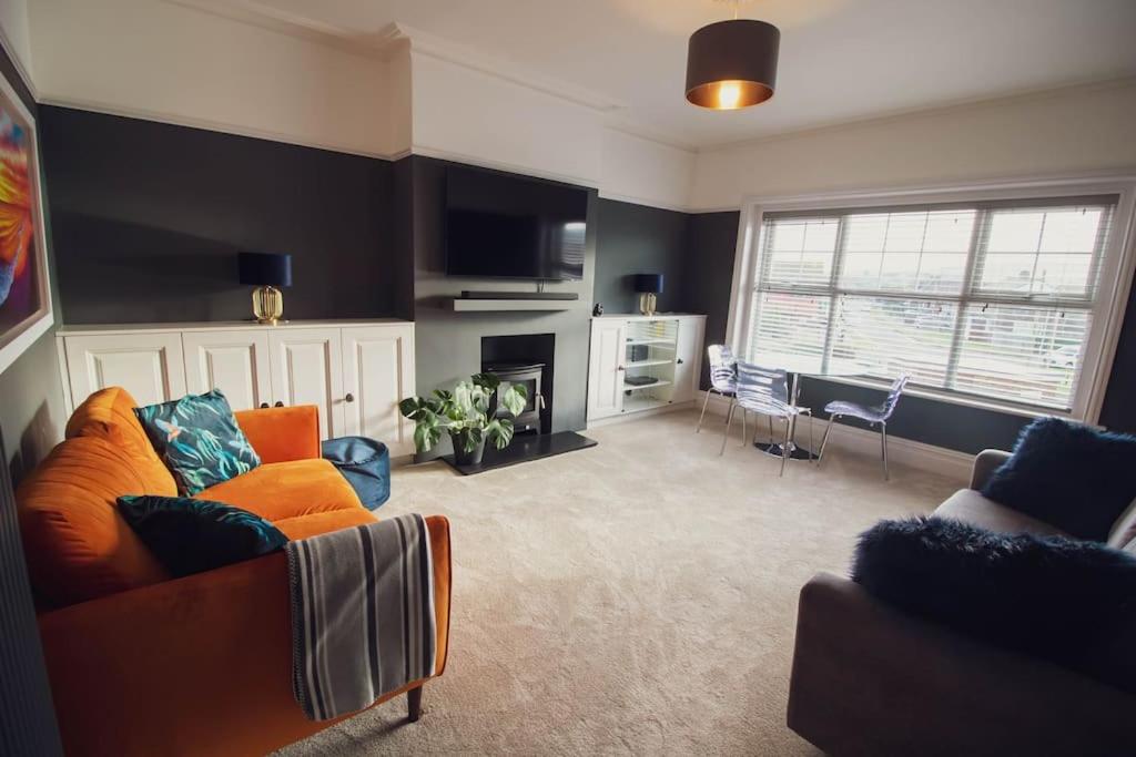 a living room with an orange couch and a fireplace at Beachy Head Apartment By Air Premier in Seaford