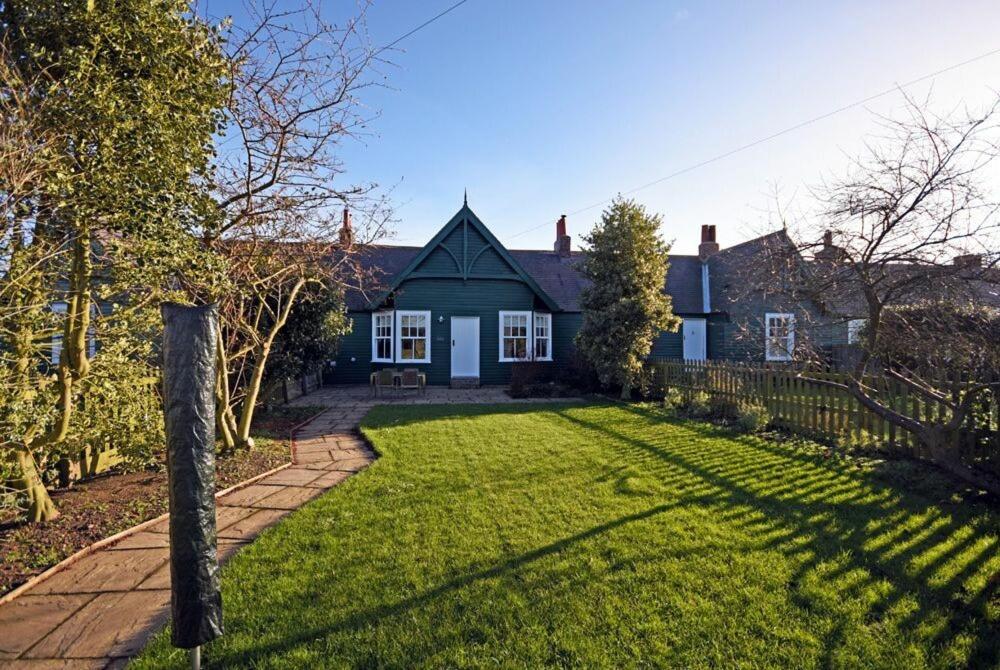 a house with a green lawn in front of it at Periwinkle in Bamburgh