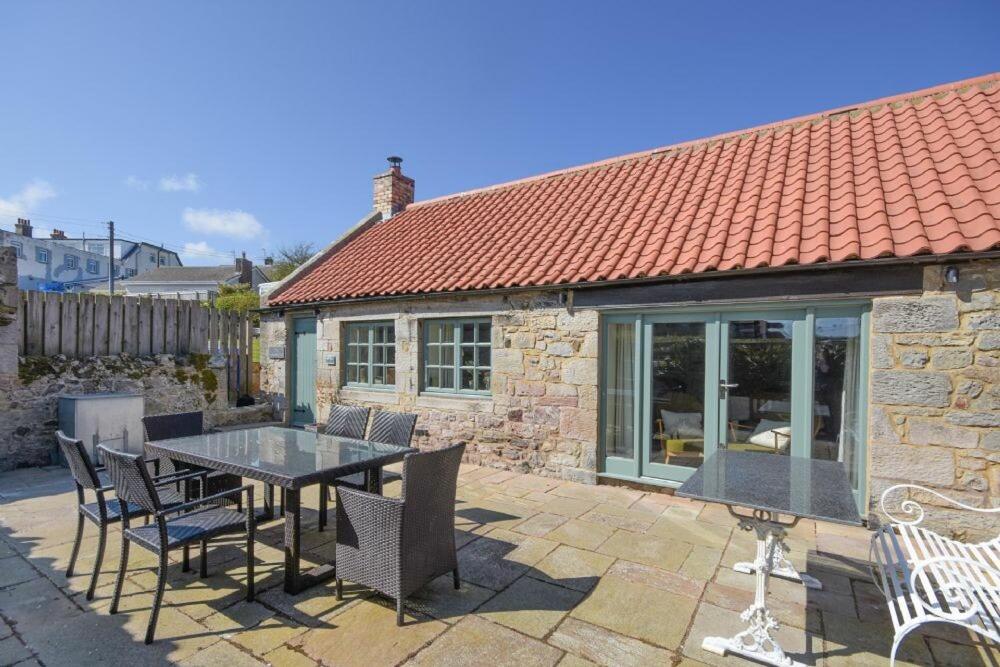 a patio with a table and chairs and a house at The Blacksmith's in Bamburgh