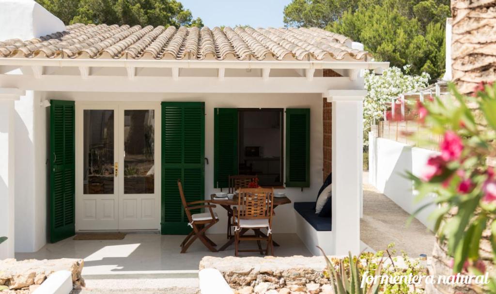 een patio met groene luiken en een tafel en stoelen bij Casas Emma y Sofía - Porto Sale - Formentera Natural in Sant Francesc Xavier