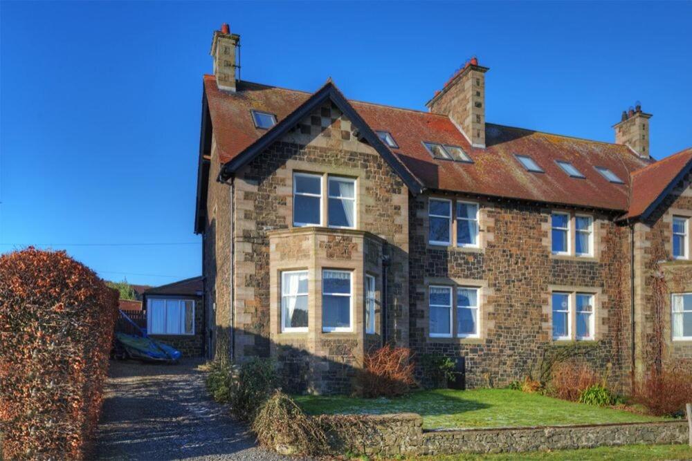 a large brick house with a red roof at The Villas No3 in Embleton