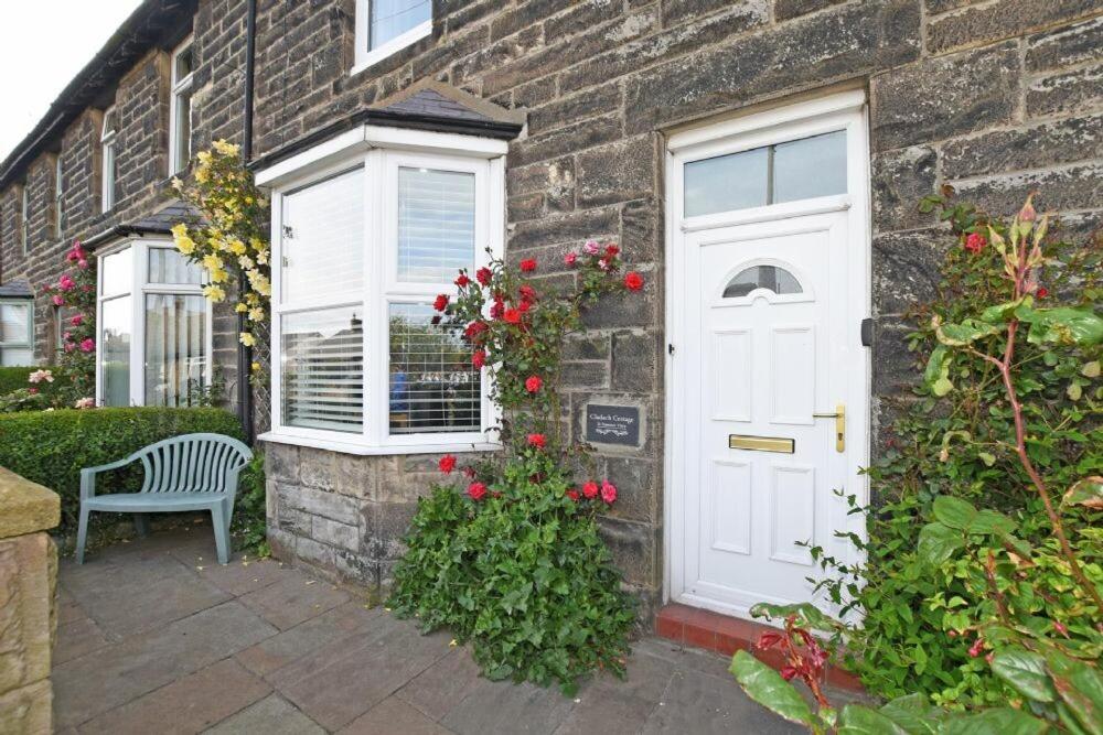 a brick house with a white door and a bench at Cladach Cottage in Seahouses