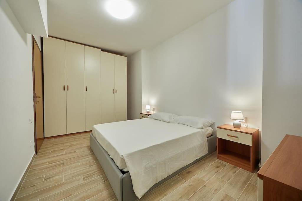 een witte slaapkamer met een bed en een houten vloer bij Flat Number 8 in Milaan