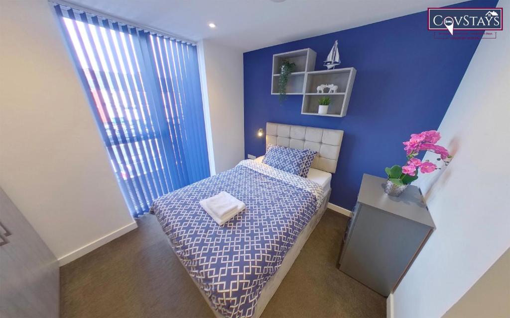 1 dormitorio con cama y pared azul en Signature House - Contemporary Studios in Coventry City Centre, free parking, by COVSTAYS, en Coventry