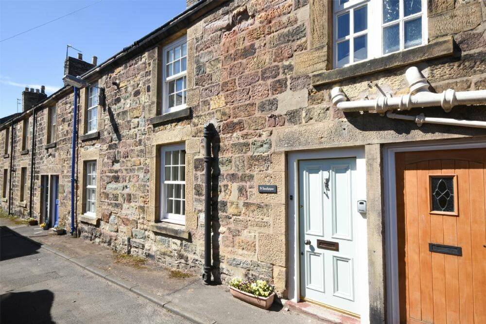 a brick building with a white door on a street at Sandpiper Alnmouth in Alnmouth