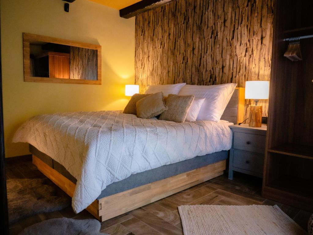 a bedroom with a bed with a wooden wall at Spirit of the Earth Cottage Dobogókő in Pilisszentkereszt