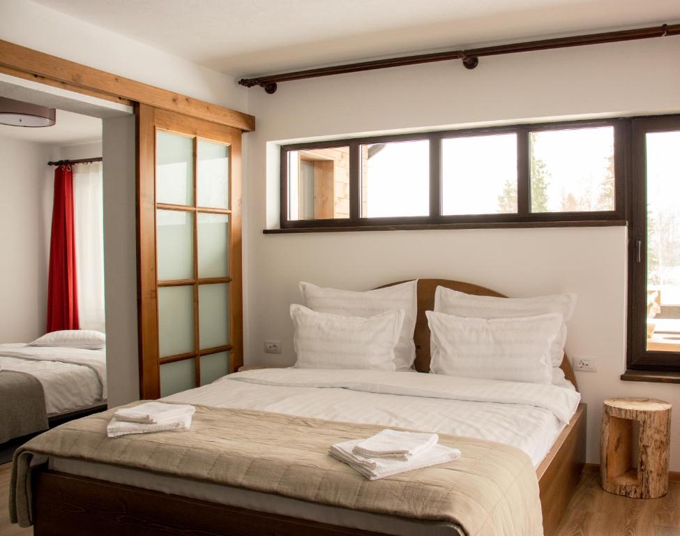 sypialnia z 2 łóżkami z białymi poduszkami i oknami w obiekcie Chalet Deluț w Suczawie