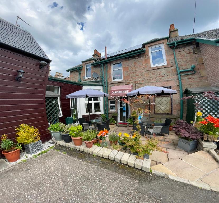 a patio with plants and umbrellas in front of a building at Carisbrooke Guest House in Inverness