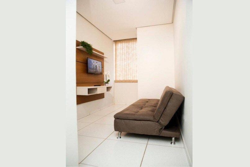 uma sala de estar com uma cadeira e uma televisão em 102-FLAT-Espaço, conforto. É disso que você precisa! em Anápolis