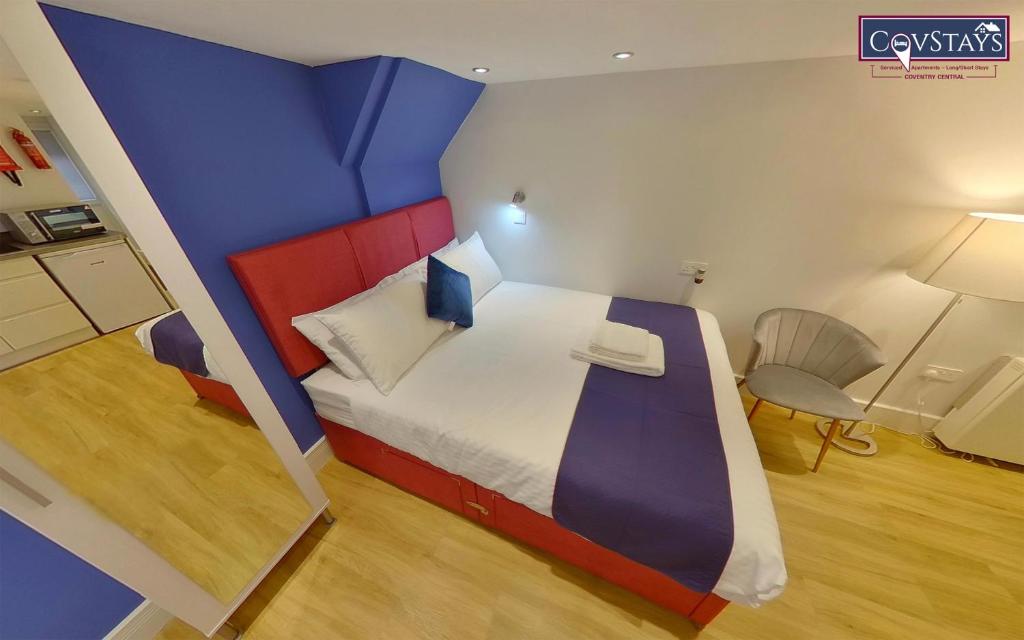 a bedroom with a bed with a blue and red headboard at Cosy Escape - Studio Apartment in Coventry City Centre in Coventry