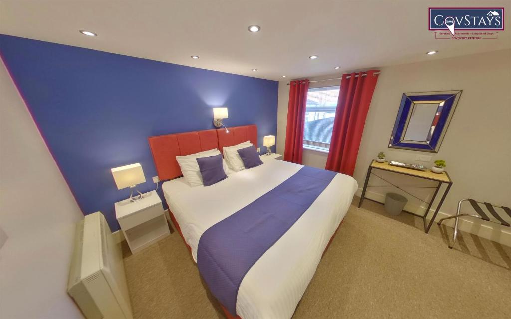 City Retreat - 1-bed Apartment in Coventry City Centre في كوفينتري: غرفة نوم بسرير كبير بجدار ازرق