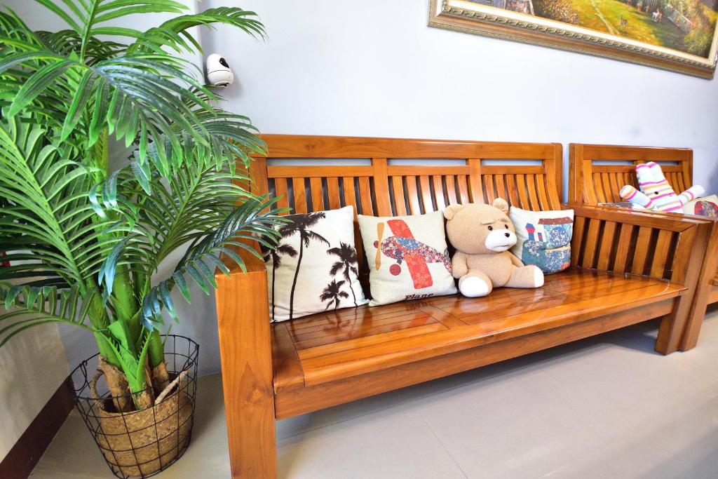 a teddy bear sitting on a wooden bench next to a plant at Piau Po 21 Inn in Taitung City