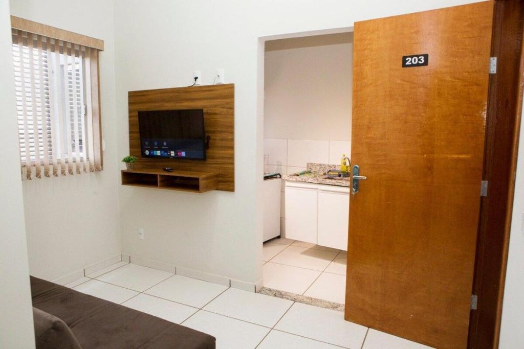 um quarto com uma cozinha e uma porta com uma televisão em 203-FLAT-Espaço,conforto.È disso que você precisa! em Anápolis