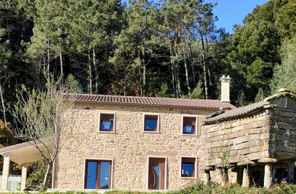 una casa de piedra con una pared de piedra y árboles en Villa Piomincha, en Cee