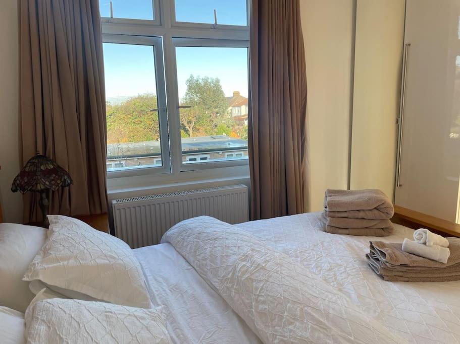 a bedroom with a bed and a large window at Premium flat! Enjoy luxurious white Egyptian bedding near Gants Hill Station, Ilford, London in Wanstead