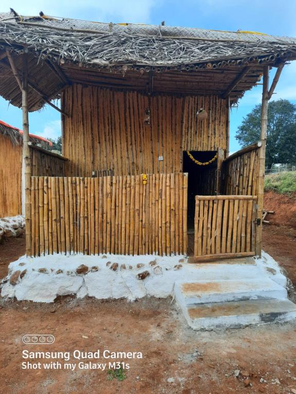 una cabaña de madera con una puerta y nieve alrededor en Moongil Kudil en Yelagiri