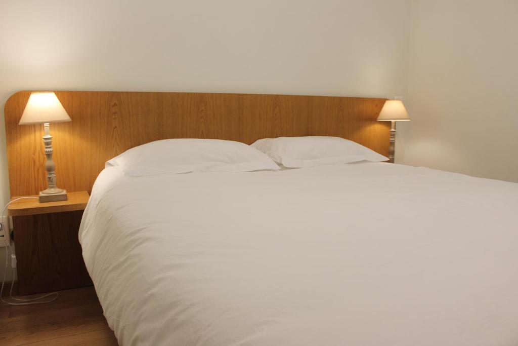 a bedroom with a large white bed with two lamps at La Bullote - Gîtes - Paris Roissy in Villeneuve-sous-Dammartin