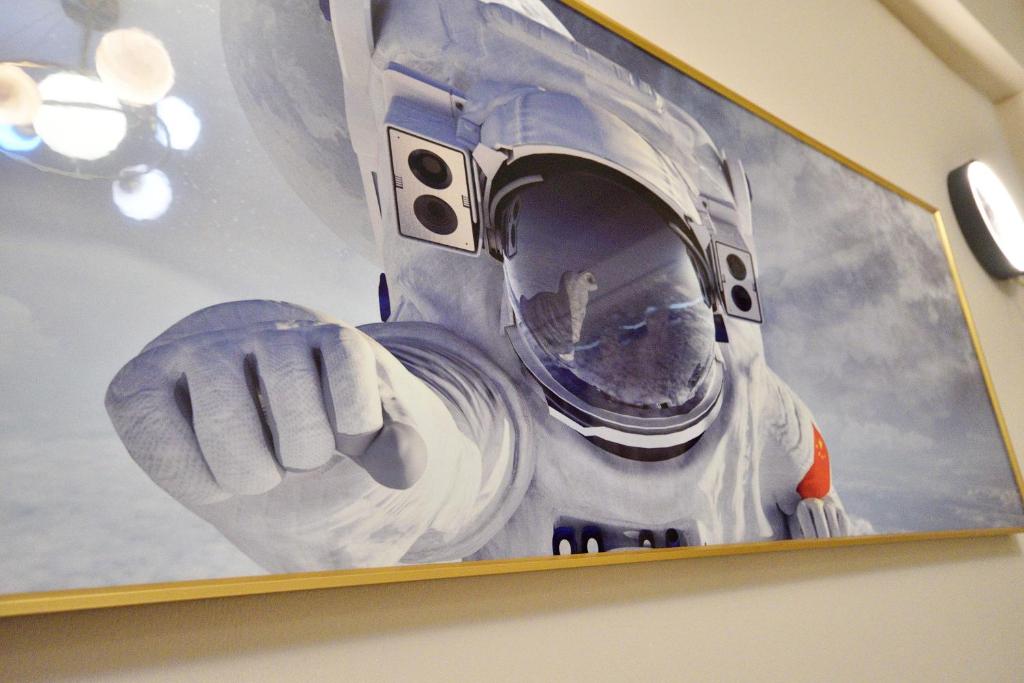 a painting of an astronaut hanging on a wall at Piau Po 21 Inn in Taitung City