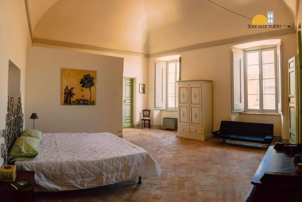um quarto com uma cama, um sofá e janelas em Appartamenti Sole alle Torri em Assis