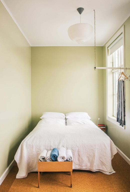 a bedroom with a bed with white sheets and a window at Hafaldan HI hostel, old hospital building in Seyðisfjörður