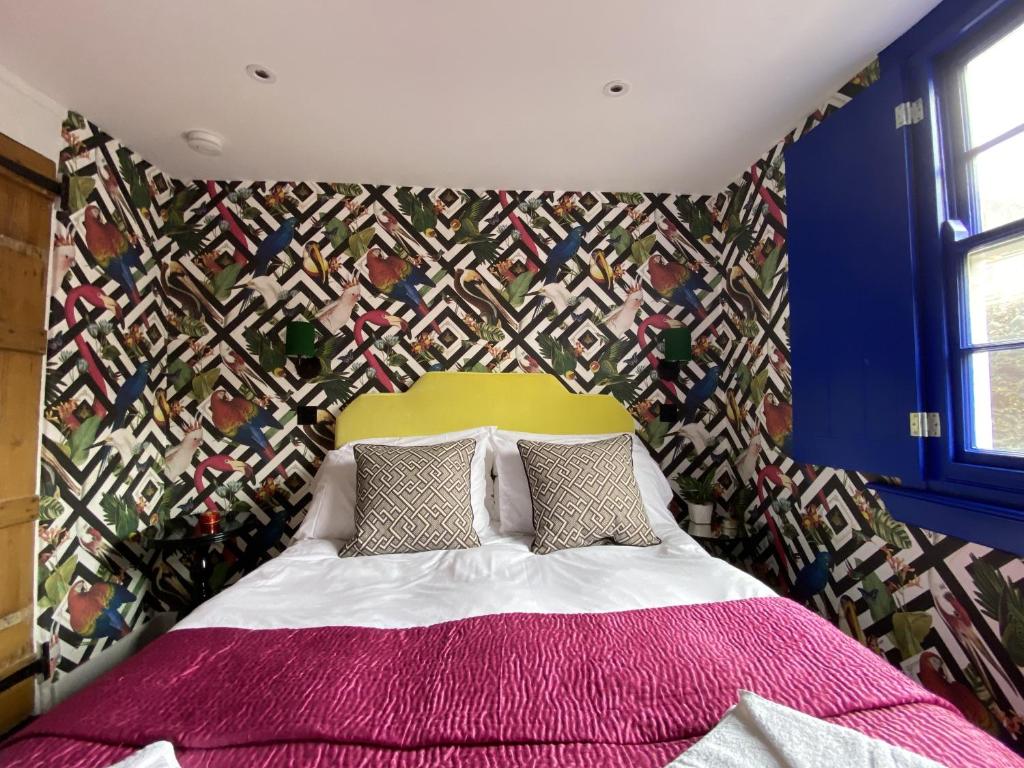 a bedroom with a bed with a colorful wall at Birdcage Heritage Cottage - city centre vibrant Brighton in Brighton & Hove