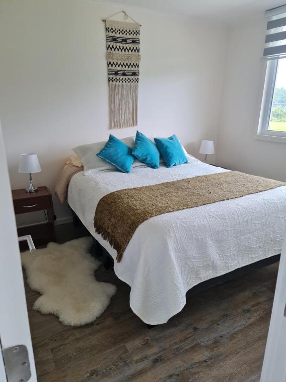 Un dormitorio con una cama con almohadas azules. en Departamento Nuevo a pasos de la playa Puerto Montt en Puerto Montt