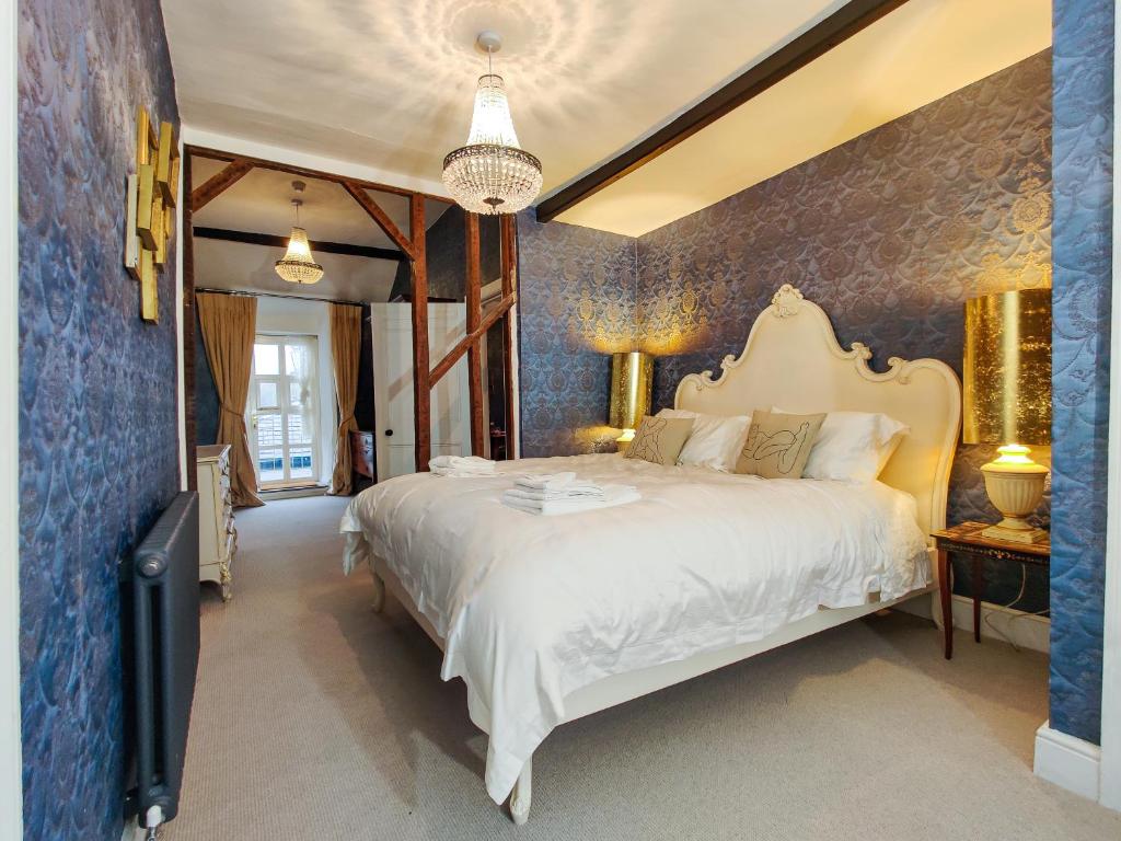 a bedroom with a large white bed and a blue wall at Plas Dolguog in Machynlleth