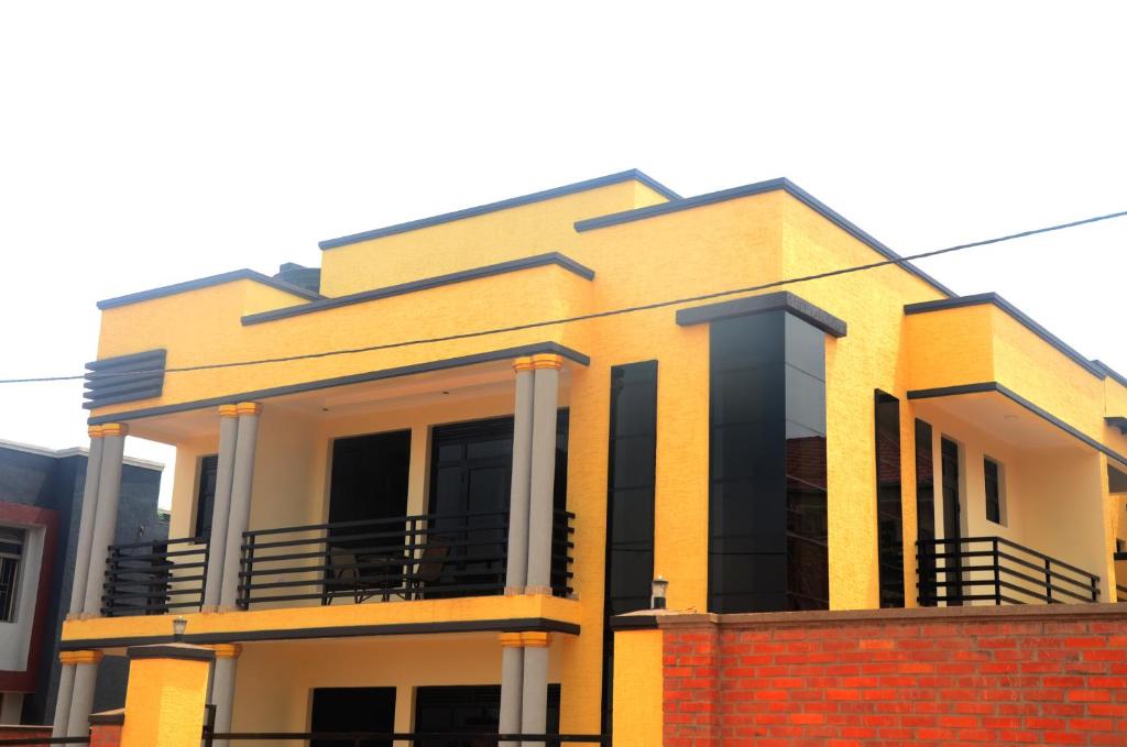 une maison jaune avec un mur en briques dans l'établissement Sunny Hill Apartments, à Kigali