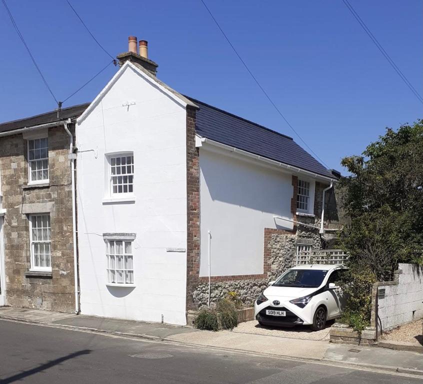 a white car parked in front of a white house at Grove Cottage in Yarmouth
