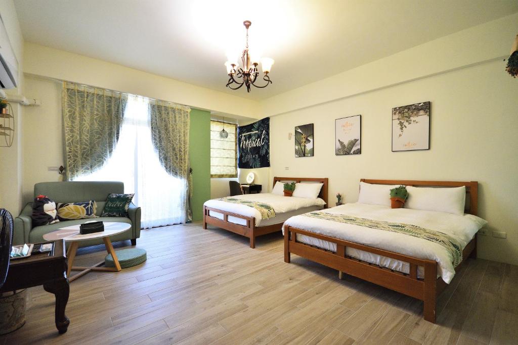 a bedroom with two beds and a couch and a chair at Piau Po 21 Inn in Taitung City