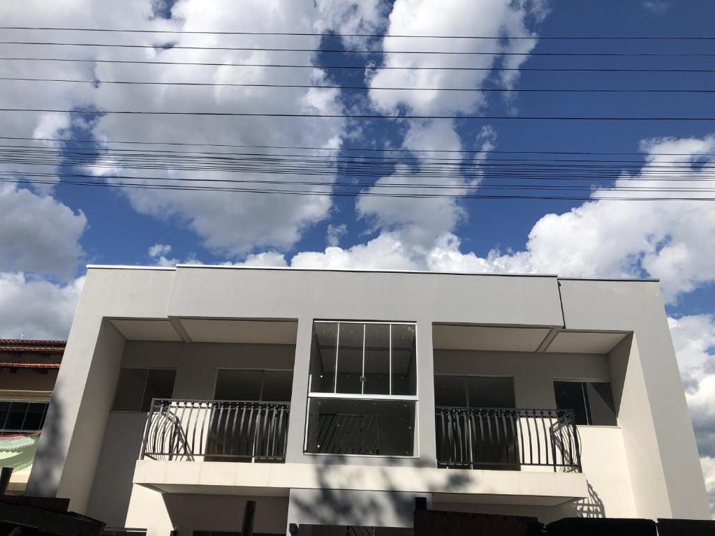un edificio blanco con balcones negros y un cielo nublado en Copas do Bosque, aluguel fixo, en Pirenópolis