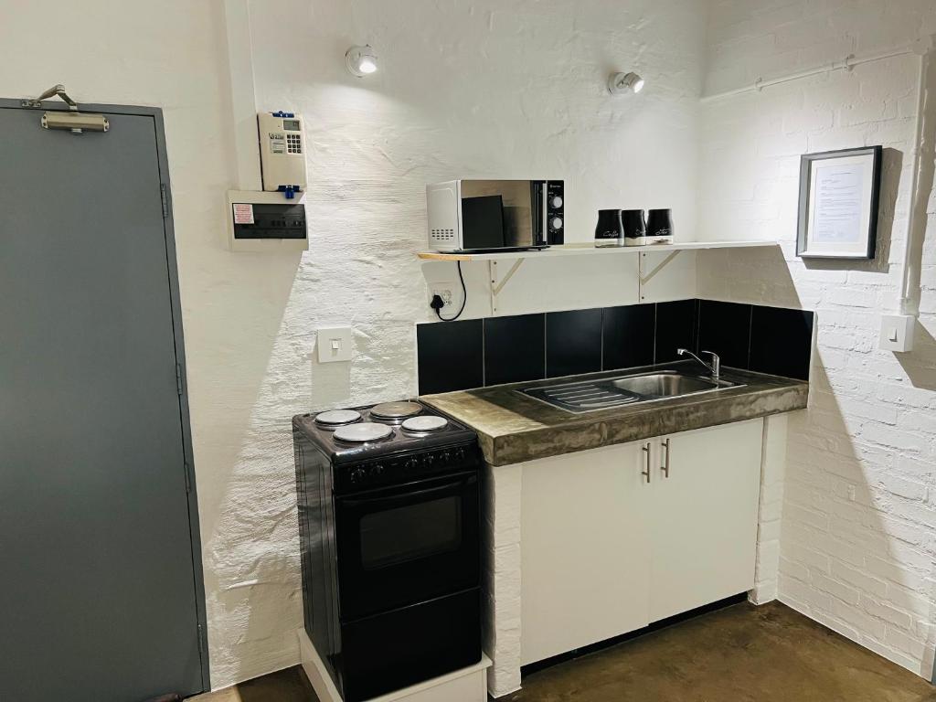 uma pequena cozinha com um lavatório e um fogão em JHB City Living 119 - fibre Wi-Fi, washing machine & big sunny balcony em Joanesburgo