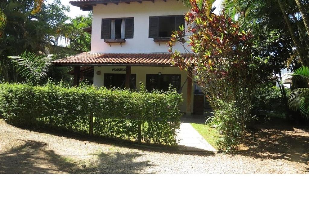 a house with a hedge in front of a building at Chalé Recanto do Barão in Boicucanga